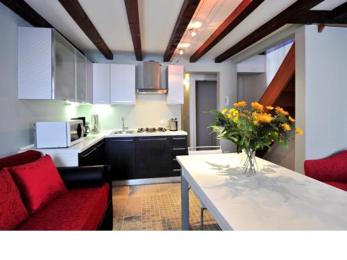 una cocina con una mesa con un jarrón de flores. en Palace La Vida Apartments, en Venecia