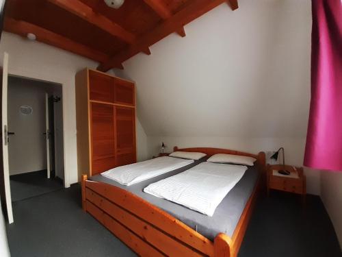 ein Schlafzimmer mit einem Holzbett in einem Zimmer in der Unterkunft Ferienwohnung Stricker  Typ B, Balkon 2/2 in Walkenried