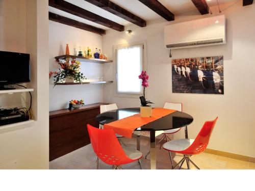 a dining room with a table and red chairs at Palace La Vida Apartments in Venice
