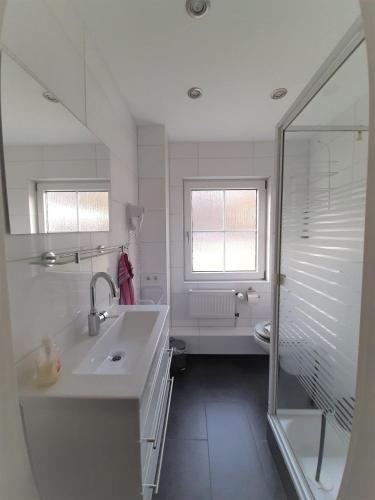 a white bathroom with a sink and a shower at Ferienwohnung-Stricker-2-1-Typ-B-Terrasse in Walkenried