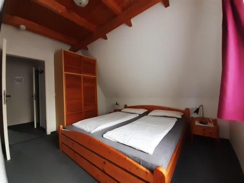 Un dormitorio con una cama de madera en una habitación. en Ferienwohnung-Stricker-B-Balkon-1-2, en Walkenried