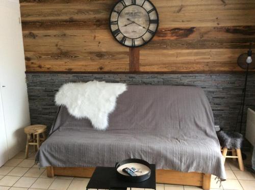 een slaapkamer met een bed met een klok aan de muur bij Le Repaire de Bellevaux aux pieds des pistes Haute Savoie in Bellevaux