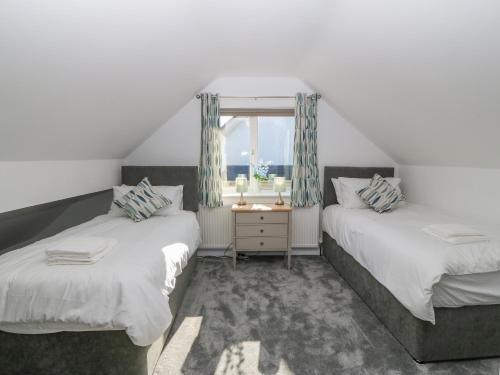 two beds in a room with a window at Treestumps in Benllech