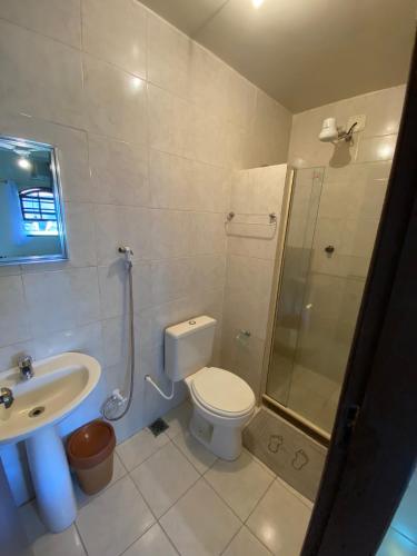 a bathroom with a toilet and a shower and a sink at Pousada Brisa da Praia in Arraial do Cabo