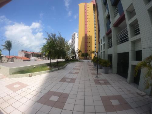 an empty sidewalk in a city with a yellow building at Aptos Privativos Vista Mar Hotel Paradise Flat in Natal