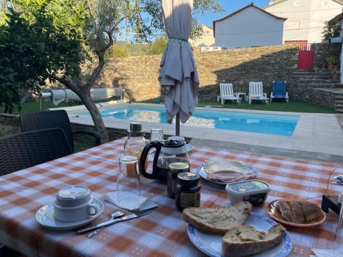 a table with food and bread on it with an umbrella at Casa da Caroline in Freixo de Espada à Cinta