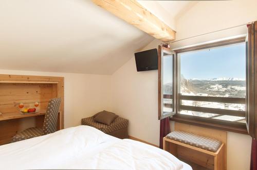 a bedroom with a bed and a large window at Hotel Due Spade in Folgaria