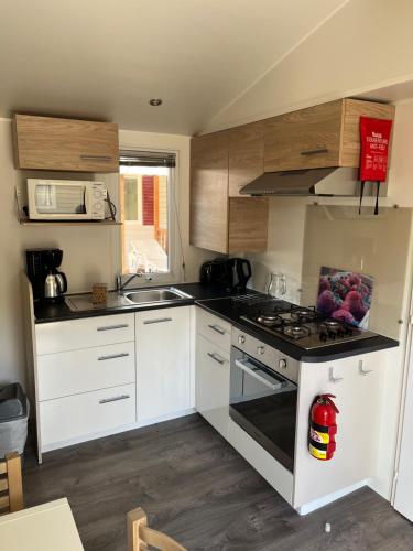 a kitchen with white cabinets and a stove top oven at Location mobil home saison 2023 in Saint-Jean-de-Monts