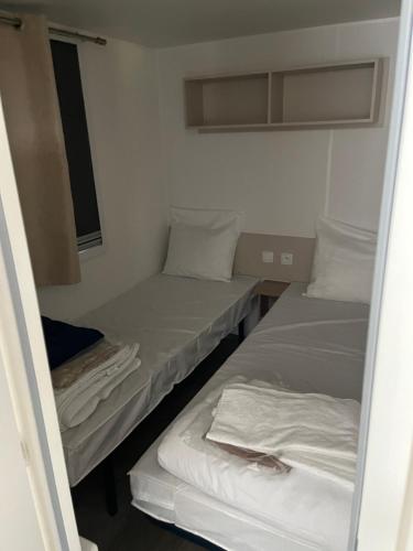 deux lits dans une petite pièce avec une fenêtre dans l'établissement Location mobil home saison 2023, à Saint-Jean-de-Monts