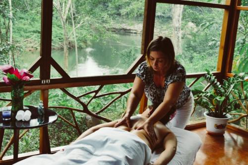 a woman is giving a man a massage at Alma Del Rio Eco-Comfort on the water in San Ignacio