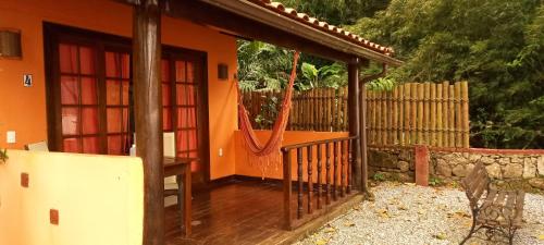 ein orangefarbenes Haus mit einer Veranda und einem Zaun in der Unterkunft Casa da Ilha Inn, Ilha Grande in Abraão