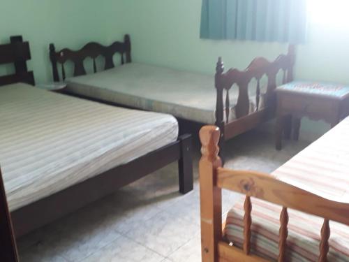 een kamer met drie bedden en een tafel en stoelen bij Praia Grande Boqueirão e Guilhermina in Praia Grande