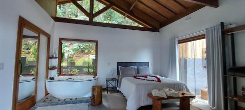 - une chambre avec un lit, une baignoire, un lit et une fenêtre dans l'établissement Chalé Au Clair de Lune Terê, à Teresópolis