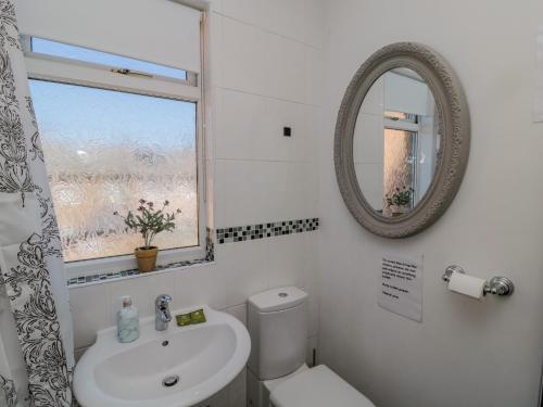 Baño blanco con lavabo y espejo en Cherry Tree House, en Morpeth