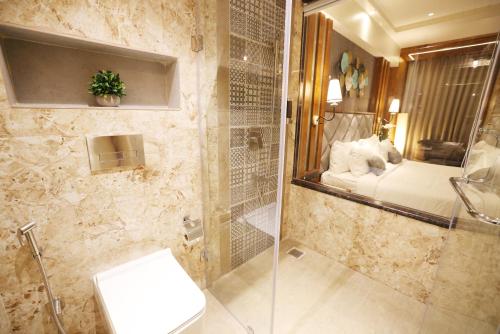 uma casa de banho com um chuveiro, um WC e um espelho. em AJ Grand Hotel em Mangalore