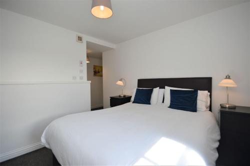 a bedroom with a large white bed with blue pillows at Puffin Apartment in Tobermory