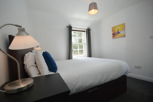 um quarto com uma cama com um candeeiro e uma janela em Dolphin Apartment em Tobermory