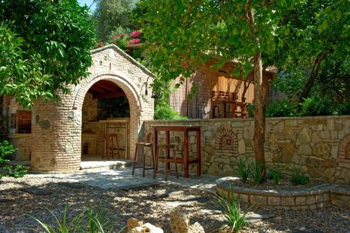 a stone house with an arch and chairs in a yard at Esperides Parga Studios in Parga