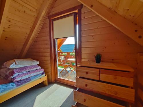 um quarto com uma cama e uma janela num chalé de madeira em Domki Letniskowe Promyk em Ustka