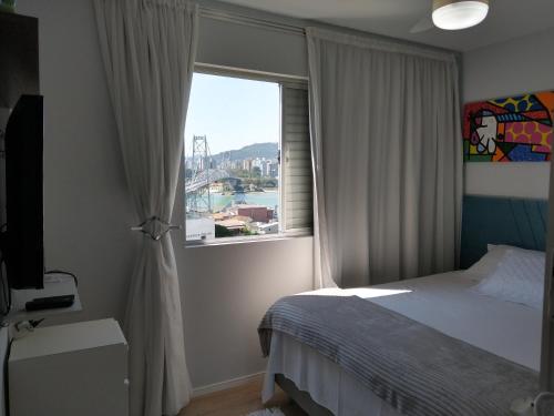 a bedroom with a bed and a large window at Magnífico "QUARTO" Privativo em Apto, com Vista Espetacular in Florianópolis