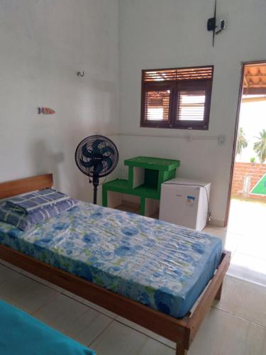 a bedroom with a bed and a green table at Pousada Yajé in Ponta do Mel