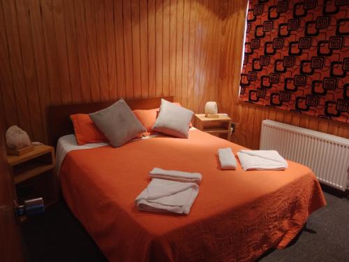 - une chambre avec un lit et des serviettes dans l'établissement ALMER HOSTAL, à Punta Arenas