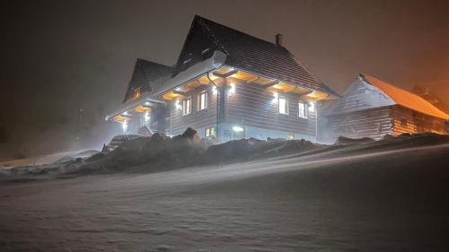 a large wooden house with lights on it at night at Chata Dolina v Bachledke in Ždiar