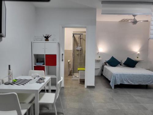 a bedroom with a bed and a table and a bathroom at Marga STUDIO H10 in Arona