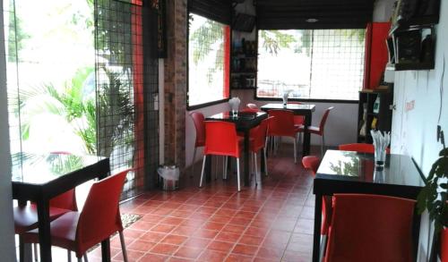 un restaurante con sillas rojas, mesas y ventanas en Bahia B&B, en Bahía de Caráquez