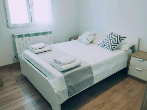 un grande letto bianco con due asciugamani sopra di Precioso apartamento en Pamplona junto al centro a Pamplona