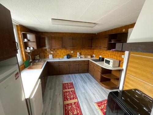 a large kitchen with wooden cabinets and a microwave at Au Bon Vieux Port Maison de vacances Alsacienne à 10mn de Ribeauvillé, Riquewihr et Kaysersberg in Sélestat