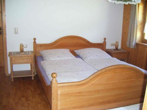 a bedroom with a wooden bed and two night stands at Ferienhof Reichart in Scheidegg