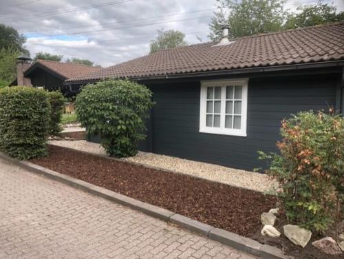 a blue house with a window and a brick driveway at Veluwse Bungalow in Ermelo