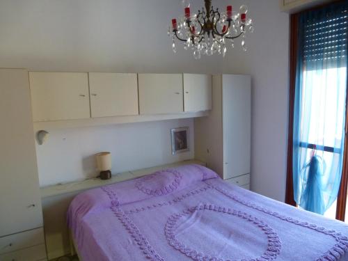 マリネッラ・ディ・サルザーナにあるAppartamento Villa Ileanaのベッドルーム(紫色のベッド、シャンデリア付)