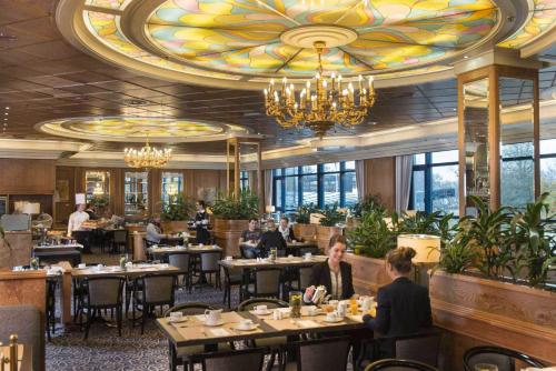 a dining room with people sitting at tables in a restaurant at Maritim Airport Hotel Hannover in Hannover