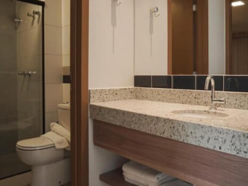 a bathroom with a sink and a toilet and a mirror at Resort Praias do Lago in Caldas Novas