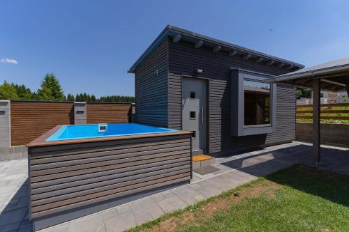 une maison noire avec une piscine dans la cour dans l'établissement APARTMÁNY POD SJEZDOVKOU, à Abertamy