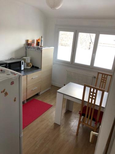 uma cozinha com uma mesa branca, uma mesa e cadeiras em Gîte de la Nièvre - Centre Ville-2e étage em Flixecourt