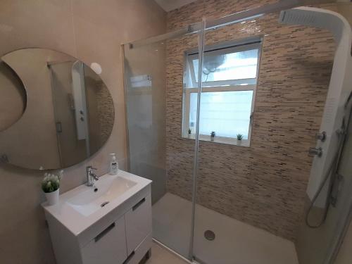 ein Bad mit einer Dusche, einem Waschbecken und einem Spiegel in der Unterkunft Cozy Central 3 Bedrooms Bragas in Porto