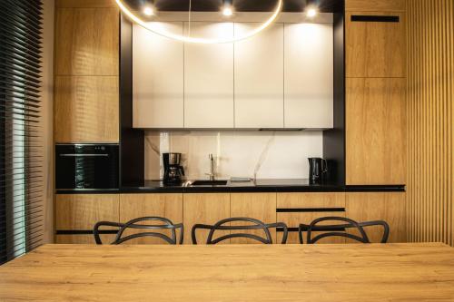 a table with chairs and a kitchen with white cabinets at Apartamenty Olimpijska by RENT4YOU in Olsztyn
