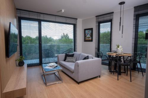 a living room with a couch and a table and windows at Apartamenty Olimpijska by RENT4YOU in Olsztyn