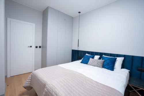a bedroom with a large white bed with blue accents at Apartamenty Olimpijska by RENT4YOU in Olsztyn