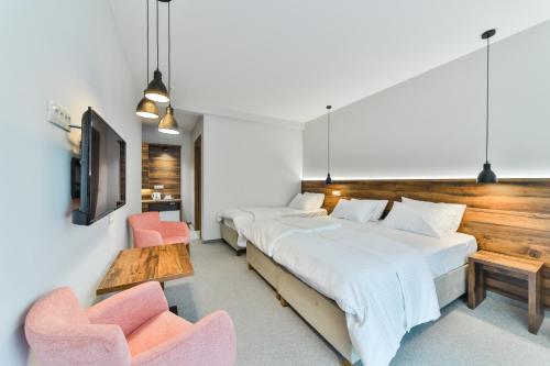 two beds in a room with two chairs and a tv at Hotel Vladimir in Budva