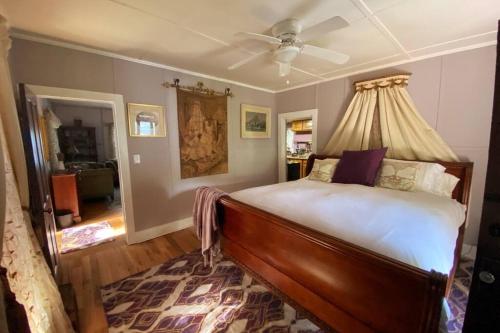 Marshall的住宿－Plum Crooked Poets Cottage - Walk to Town - Luxury King Bed - Near Asheville - Excellent Wi-Fi，一间卧室配有一张带吊扇的床