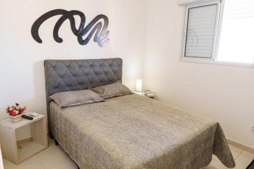 1 dormitorio con 1 cama y un cartel en la pared en VISTA PRAIA MAR - AVIAÇÃO - 300 metros da praia - WI FI - VARANDA GOURMET com CHURRASQUEIRA - ESTACIONAMENTO gratuito en Praia Grande