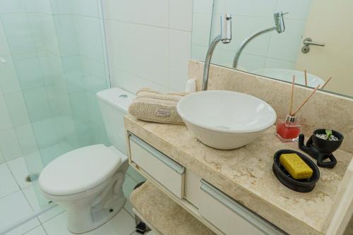 a bathroom with a sink and a toilet and a mirror at VISTA PRAIA MAR - AVIAÇÃO - 300 metros da praia - WI FI - VARANDA GOURMET com CHURRASQUEIRA - ESTACIONAMENTO gratuito in Praia Grande
