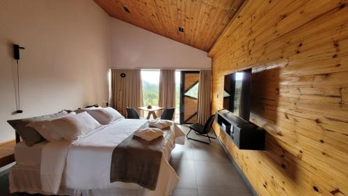 a bedroom with a bed and a tv and a wooden wall at Hotel Pico 16 in Monte Verde