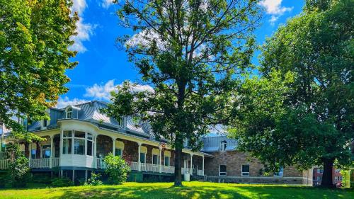 a large house with a tree in front of it at Auberge Le St-Alexis in La Baie