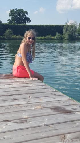 a woman sitting on a dock in the water at Wohnhaus City Süd in Herzogsdorf