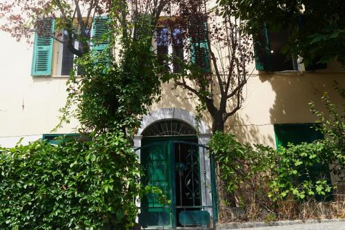 a building with a green door and a tree at Casa Eugénie l'appartement de tante Madeleine vue sur les montagnes in Venaco